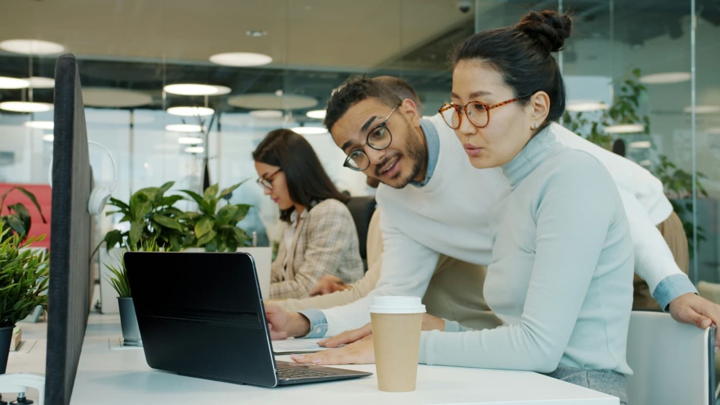 Two colleagues reviewing work on a laptop